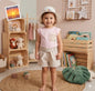 The Nile Luxuries toddler outfit with a pink cap-sleeve top, striped linen shorts, and a floral sun hat in a nursery.