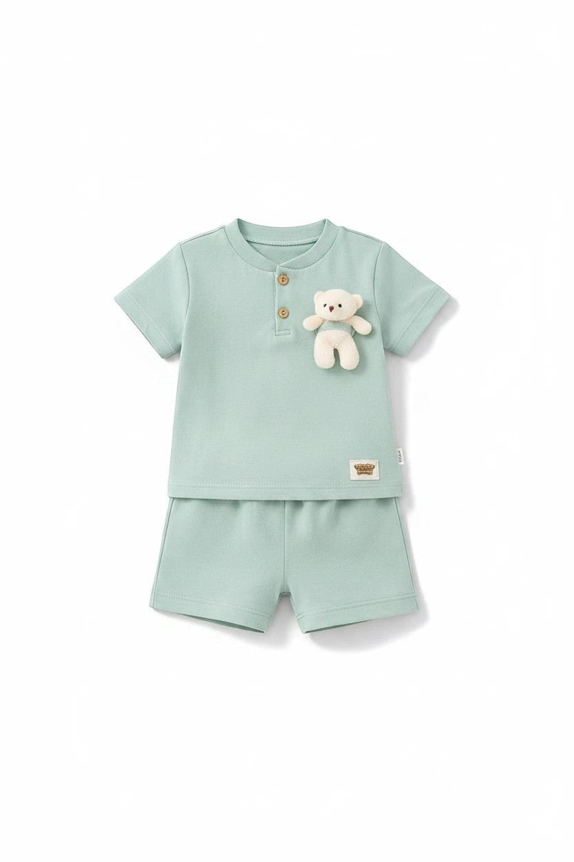The Nile Luxuries sage green toddler shirt and shorts set with a plush teddy bear appliqué and henley neckline.