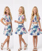 The Nile Luxuries girls two-piece set with a tropical palm tree print crop top and tiered skirt in pink and blue.
