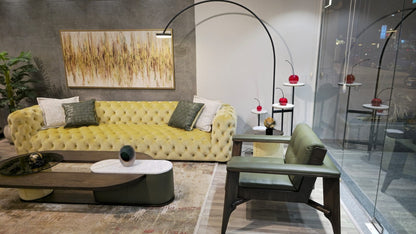 The Nile Luxuries tufted chartreuse velvet sofa with deep button-tufting and decorative pillows. A matching armchair is visible.
