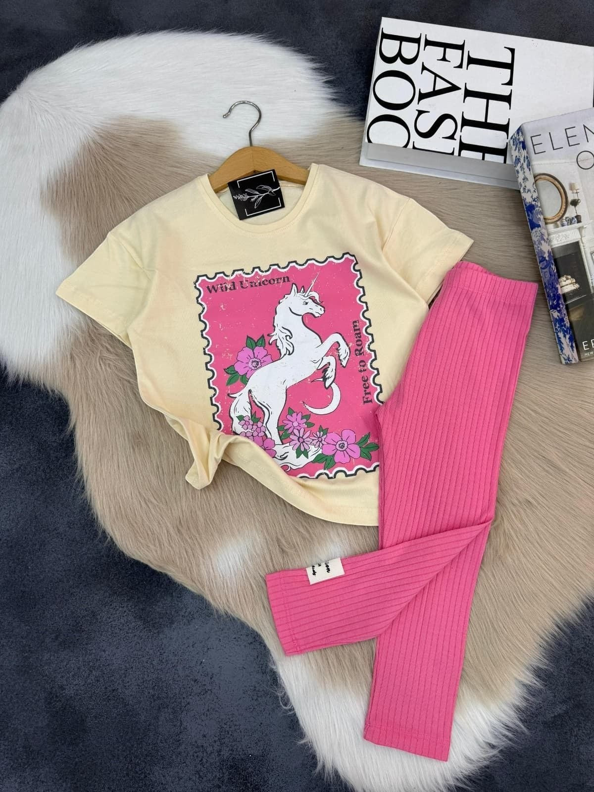 The Nile Luxuries girls two-piece set with a cream unicorn graphic t-shirt and pink ribbed leggings.