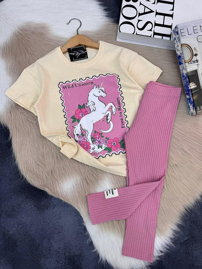The Nile Luxuries unicorn graphic t-shirt and pink ribbed leggings set for kids on a soft faux fur background.