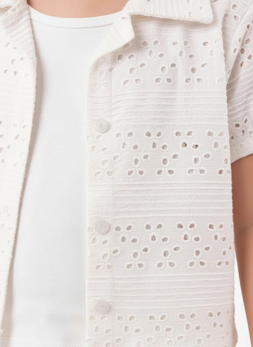 The Nile Luxuries white eyelet embroidered button-down shirt with a classic collar and delicate floral pattern.