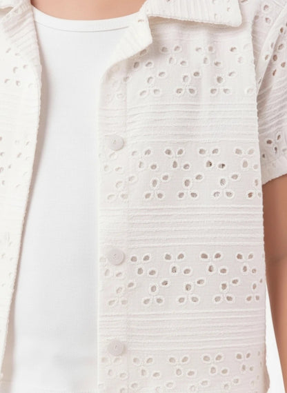 The Nile Luxuries white eyelet embroidered button-down shirt with a classic collar and delicate floral pattern.