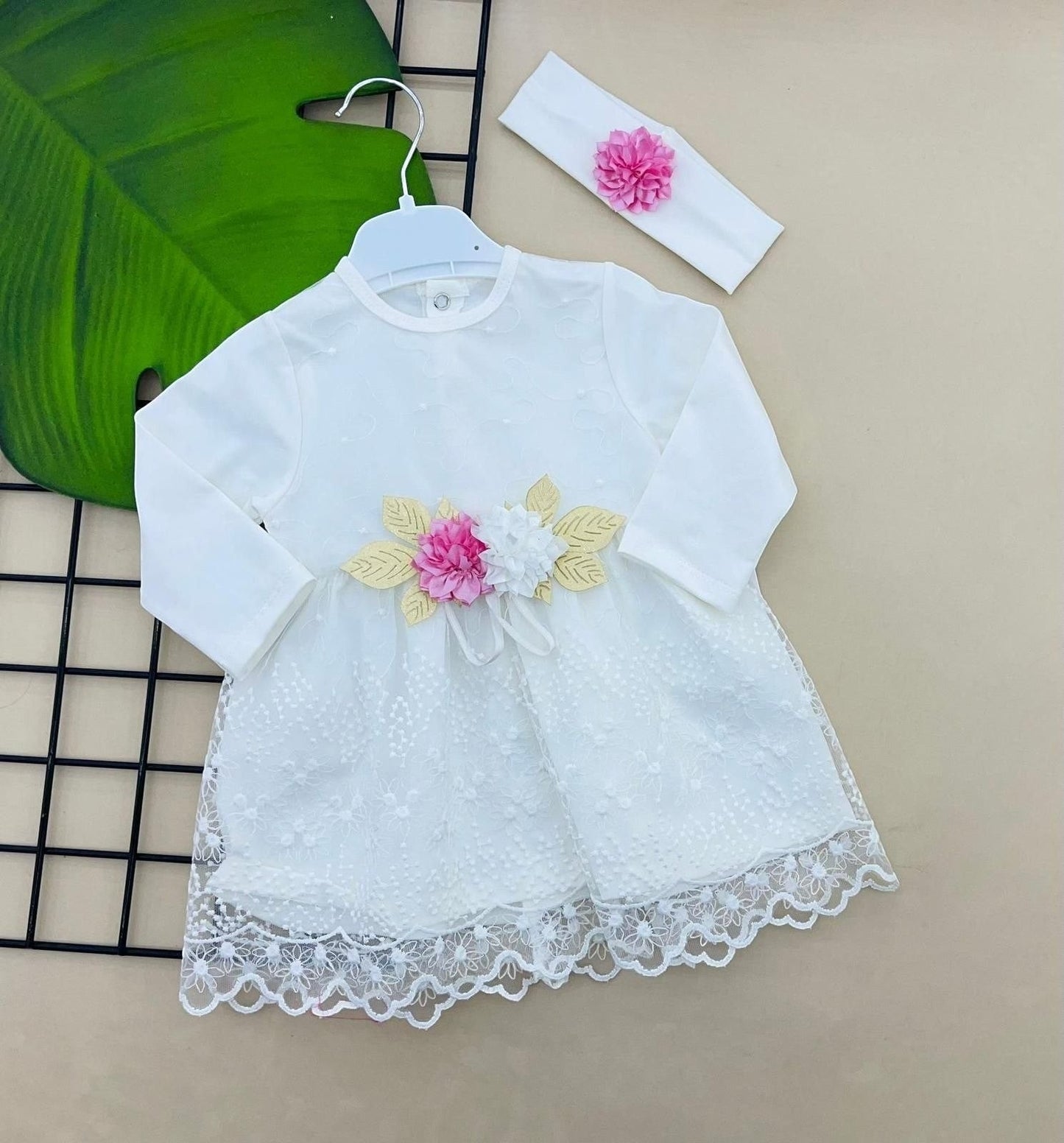 The Nile Luxuries white lace baby dress with pink and white floral applique and matching headband.