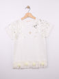 The Nile Luxuries white cotton t-shirt with metallic leaf print, gold heart emblem, and ruffled hem with fabric roses.