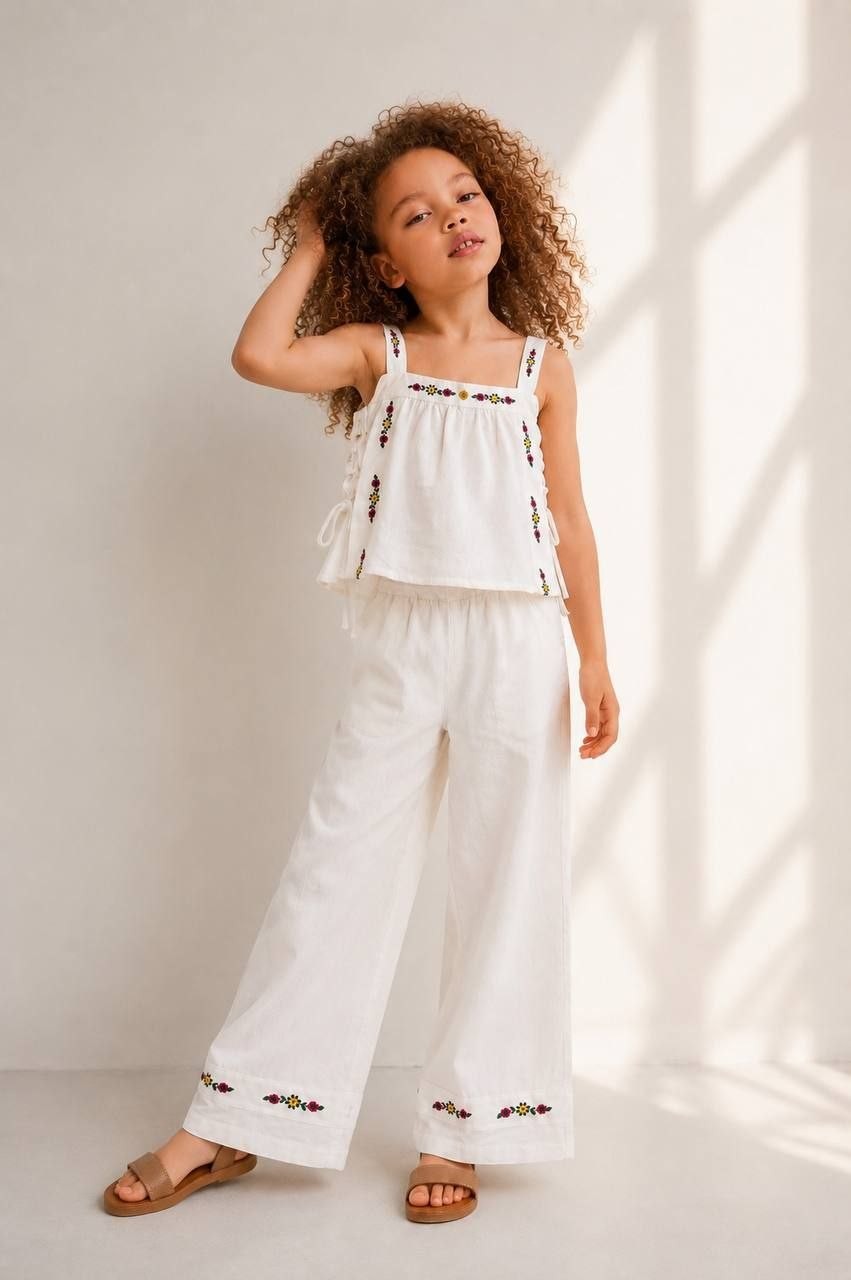 The Nile Luxuries white linen blend set with embroidered crop top and wide leg pants. Floral embroidery in yellow, red, purple.