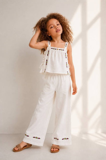 The Nile Luxuries white linen blend set with embroidered crop top and wide leg pants. Floral embroidery in yellow, red, purple.