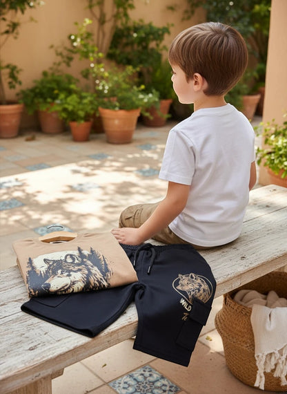 The Nile Luxuries boy's outfit set with a wolf graphic t-shirt and black cargo shorts on a wooden bench.