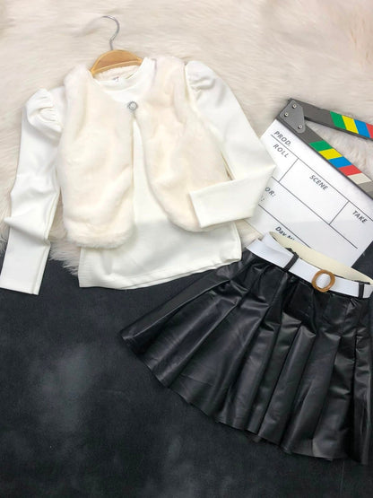 The Nile Luxuries three-piece youth outfit with a white ribbed top, plush faux-fur vest, and black pleated skirt.