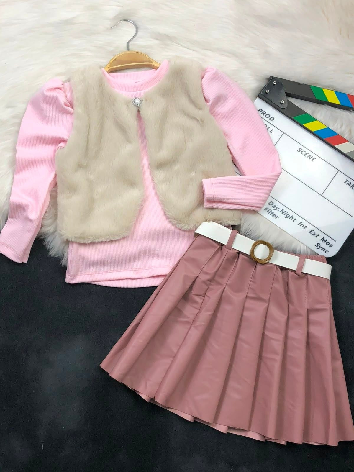 The Nile Luxuries three-piece youth set with a pink ribbed top, plush faux-fur vest, and pleated faux-leather skirt.