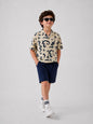 The Nile Luxuries short sleeve collared shirt with abstract navy print on cream fabric. Boy wearing shirt and navy shorts.