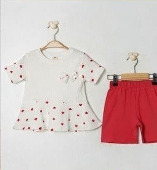 The Nile Luxuries baby girls white short-sleeve tunic with red heart print and peplum hem, paired with red shorts.