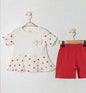 The Nile Luxuries baby girls white short-sleeve tunic with red heart print and peplum hem, paired with red shorts.