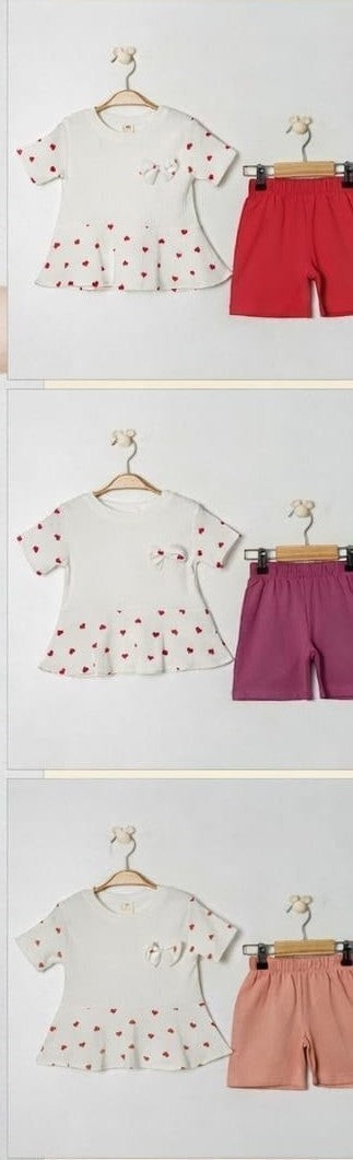 The Nile Luxuries baby girls white tunic with red heart print and peplum hem, paired with red shorts.