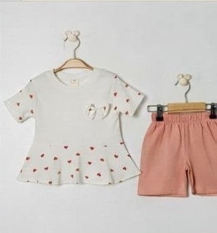 The Nile Luxuries baby girls white short-sleeve tunic with red heart print and peplum hem, paired with coral shorts.