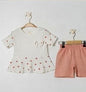The Nile Luxuries baby girls white short-sleeve tunic with red heart print and peplum hem, paired with coral shorts.