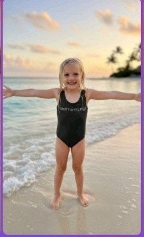 The Nile Luxuries black one-piece swimsuit with graphic logo on a young girl at the beach.