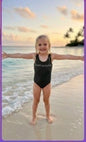 The Nile Luxuries black one-piece swimsuit with graphic logo on a young girl at the beach.