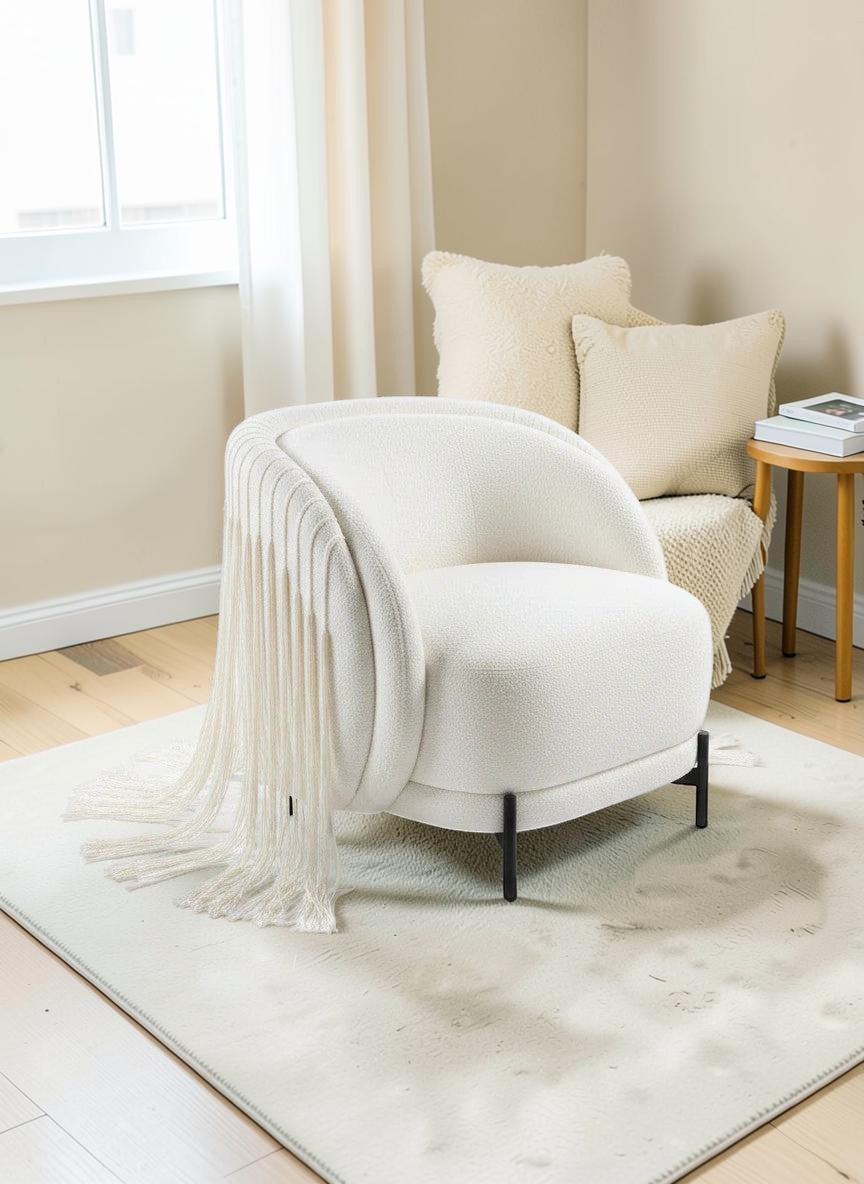 The Nile Luxuries cream boucle armchair with dramatic fringe detailing and black legs.
