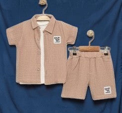 The Nile Luxuries boys' beige gauze shirt and shorts set. Short-sleeved collared shirt with button-down front and elastic-waist shorts, both with embroidered patch.