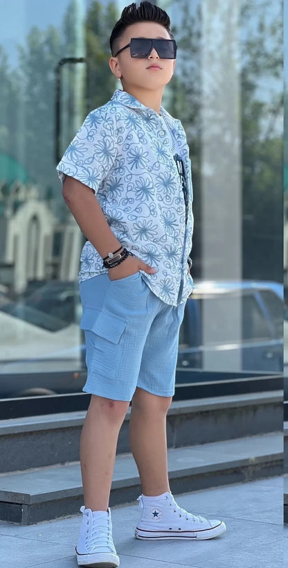 The Nile Luxuries boys' light blue printed short sleeve button-up shirt and cargo shorts set with white high-top sneakers.