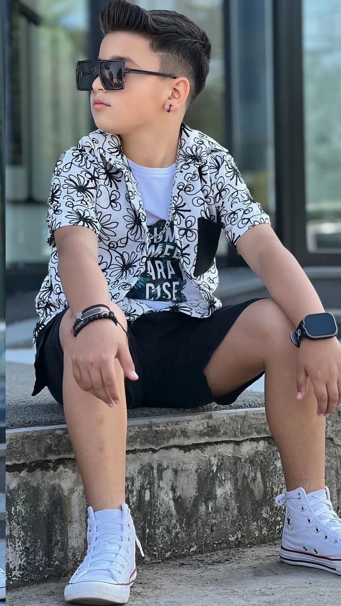 The Nile Luxuries boys' white short sleeve button-up shirt with black floral print and black shorts.