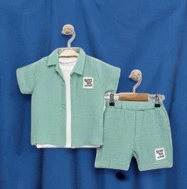The Nile Luxuries boys mint green gauze shirt and shorts set with embroidered patch. Short-sleeved collared shirt and elastic-waist shorts.