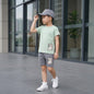 The Nile Luxuries boys' light sage green t-shirt and grey shorts set with checkered patch detail.