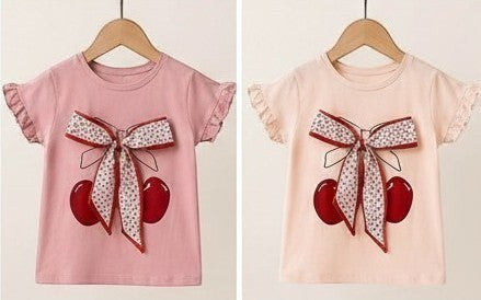 The Nile Luxuries Girls cherry print short sleeve t-shirt with ruffled sleeves and a bow accent. Available in pink and peach.