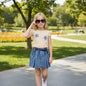 The Nile Luxuries Girls Denim Skirt and T-shirt Set. Cream tee with floral appliques, blue pleated denim skirt with elastic waist.