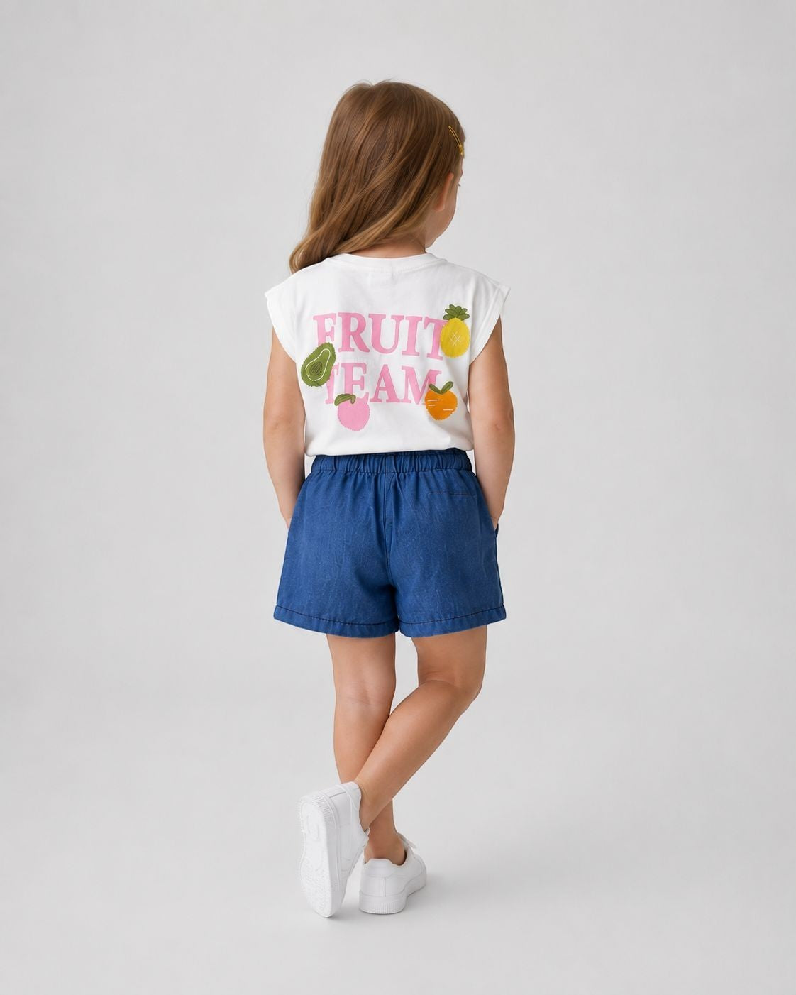 The Nile Luxuries Girls white sleeveless top with "Fruit Team" graphic and embroidered fruits, paired with blue denim shorts.