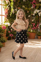 The Nile Luxuries girls' polka dot skirt set with a ruffled beige top and black skirt with white polka dots and bow.