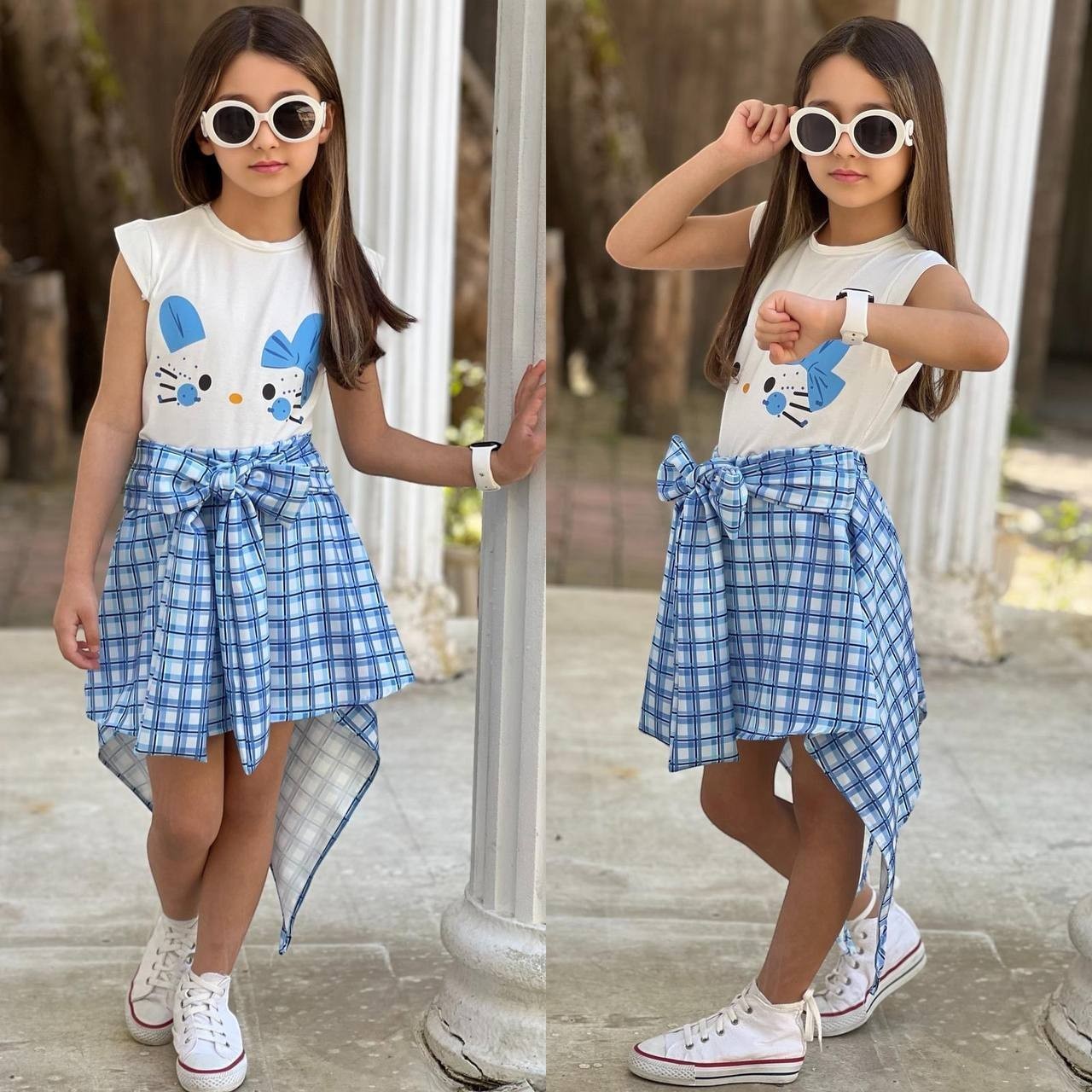 The Nile Luxuries girls' white sleeveless top with blue character graphic and blue plaid handkerchief hem skirt with tie waist.