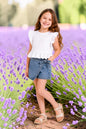 The Nile Luxuries girls white cotton ruffled sleeve peplum top and denim skort set with bow detail.
