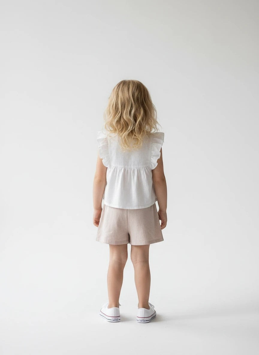 The Nile Luxuries girls' white ruffled sleeve top with floral embroidery and beige pleated shorts.