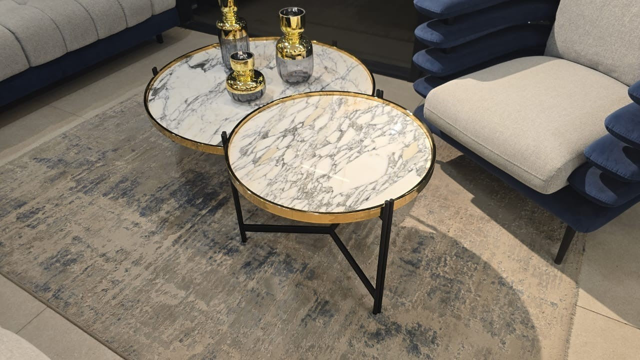 The Nile Luxuries nesting coffee tables with white and grey marble tops and gold trim, on black metal legs.