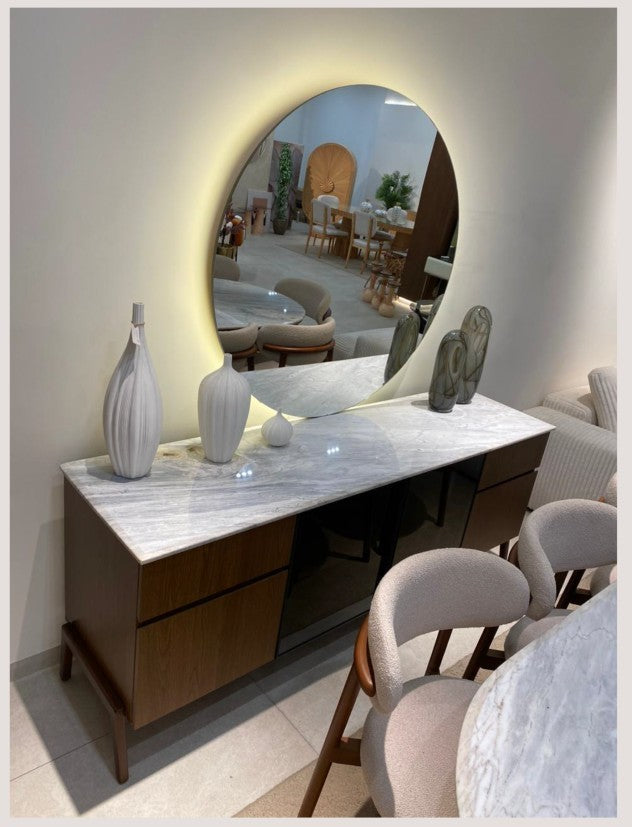 The Nile Luxuries modern oval marble dining table with dark wood base and upholstered chairs. Features natural marble top with unique veining.