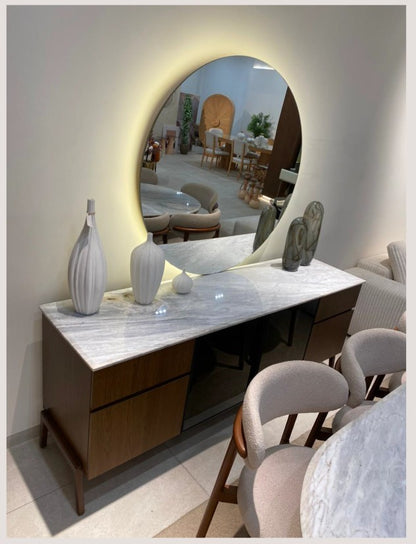 The Nile Luxuries modern oval marble dining table with dark wood base and upholstered chairs. Features natural marble top with unique veining.
