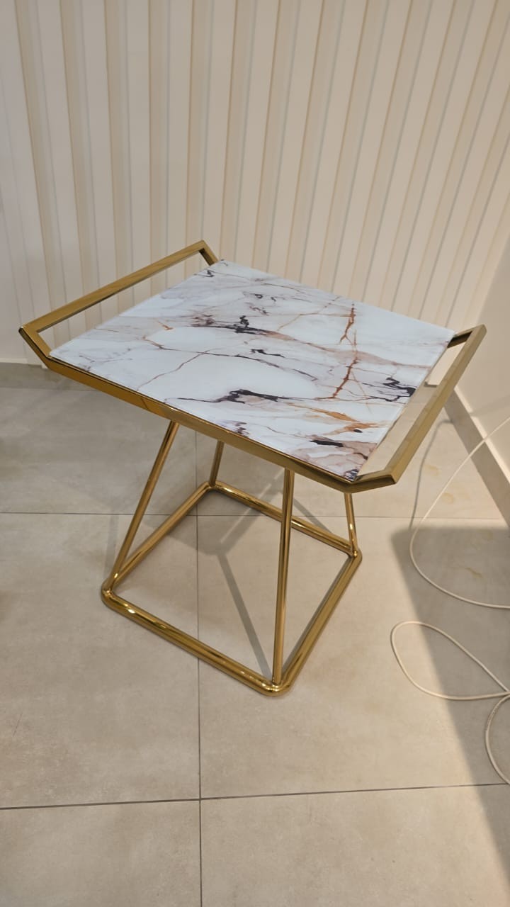 The Nile Luxuries modern accent table with white marble-look top and gold geometric base.