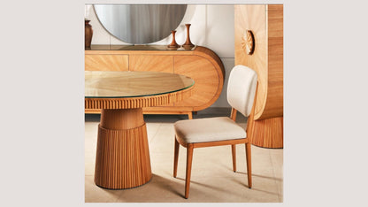 The Nile Luxuries oval dining table with fluted wood base and clear glass top, paired with a cream upholstered chair.