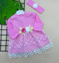The Nile Luxuries baby girl's pink dress with white lace overlay, floral appliqué, and matching headband.