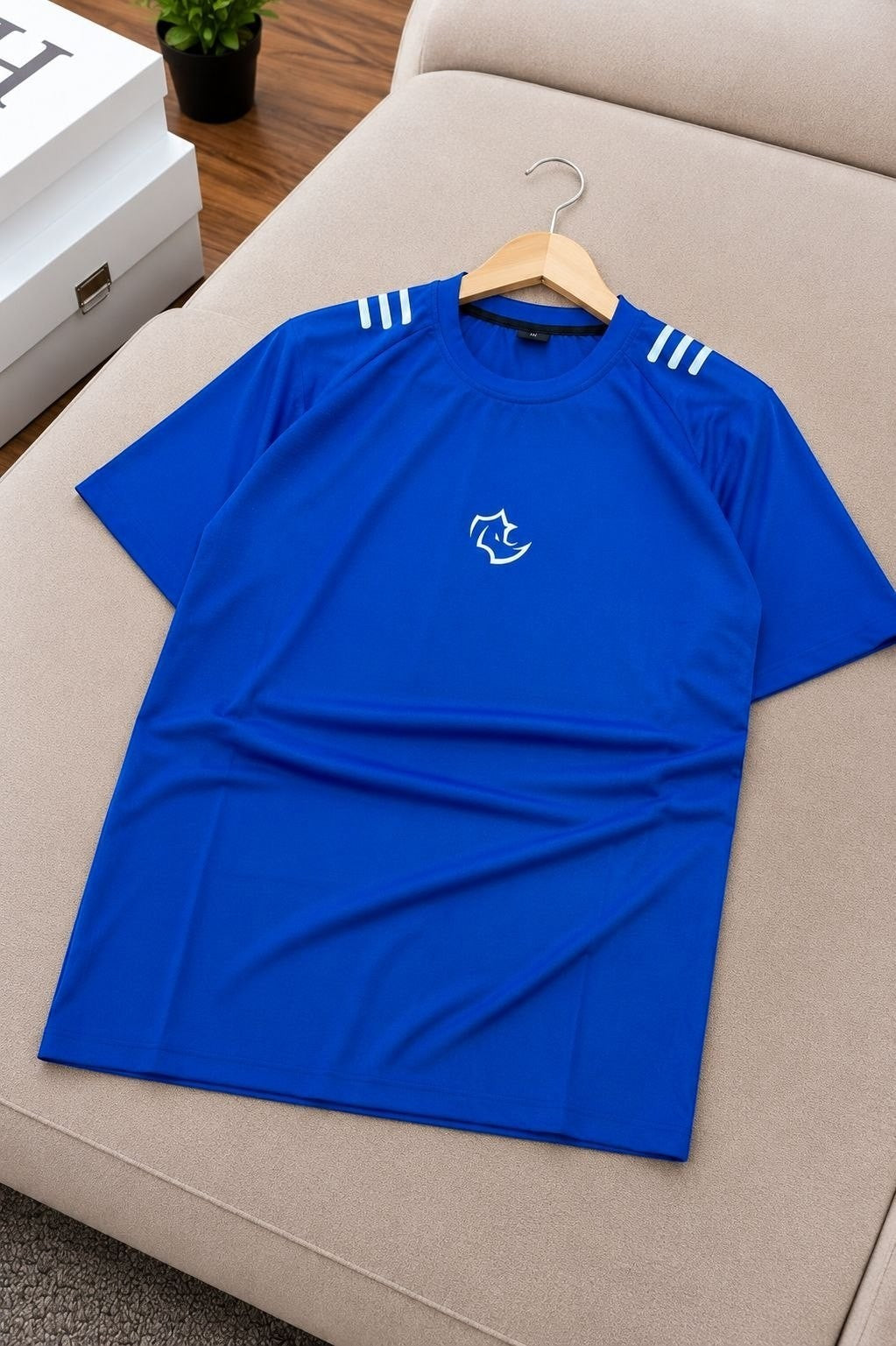 The Nile Luxuries royal blue athletic t-shirt with white graphic logo and three white stripes on shoulders. Lightweight, breathable fabric.