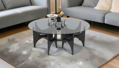 The Nile Luxuries round smoked glass coffee table with a sculptural matte black base. Modern design.