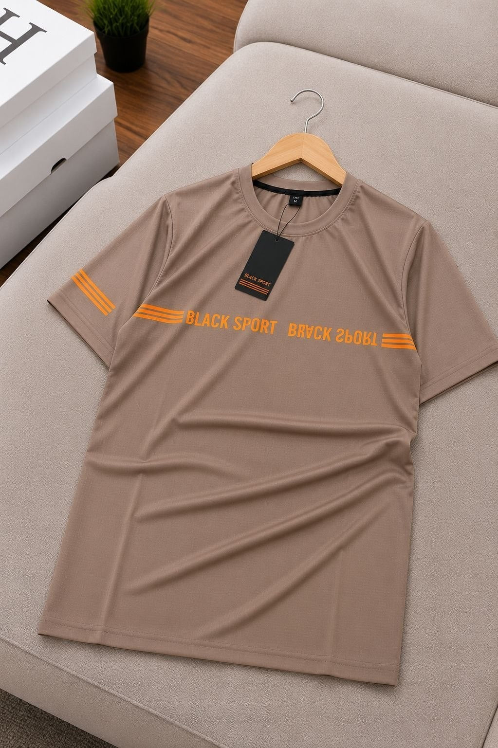 The Nile Luxuries taupe short sleeve t-shirt with orange graphic detail and stripes on sleeve.