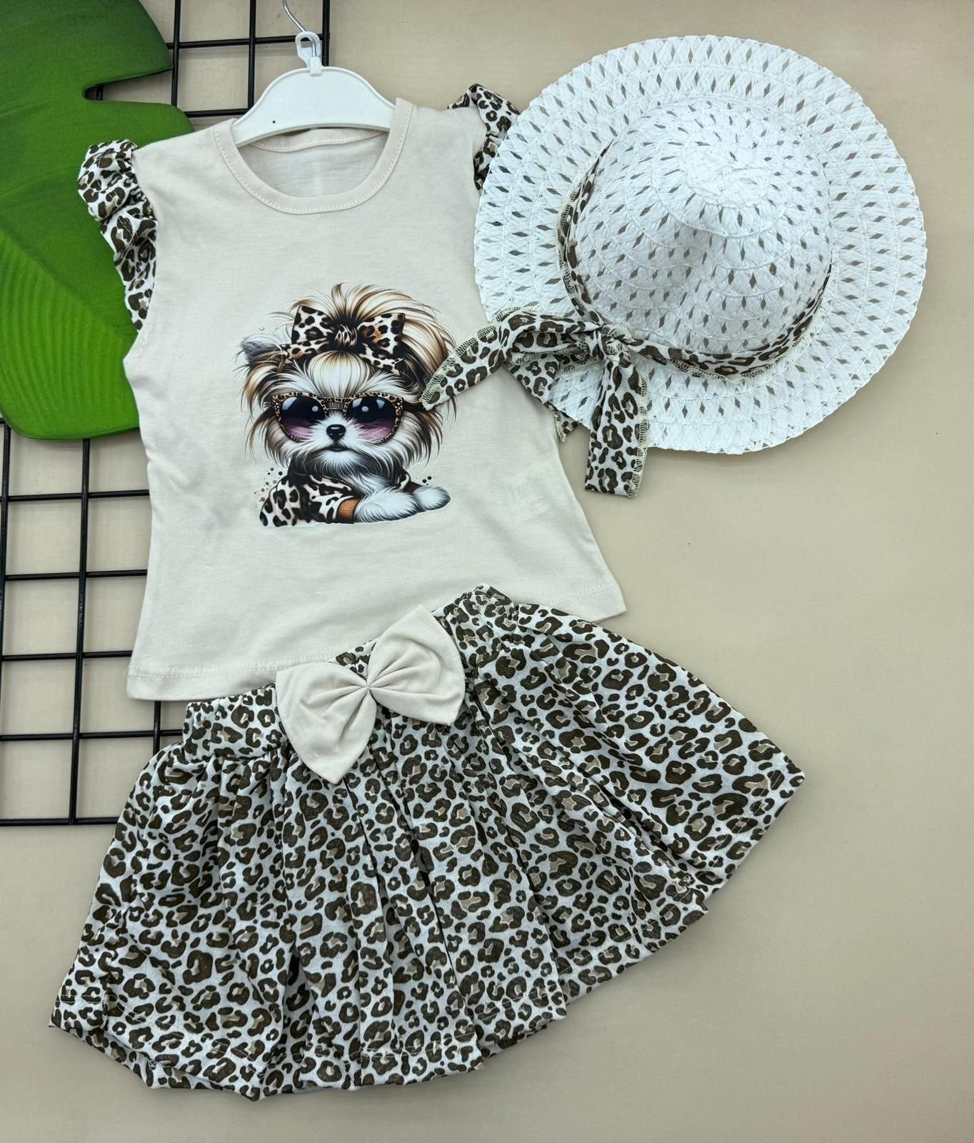 The Nile Luxuries toddler girl's 3-piece outfit: sleeveless top with dog graphic, leopard print skirt, and matching hat. Cotton.