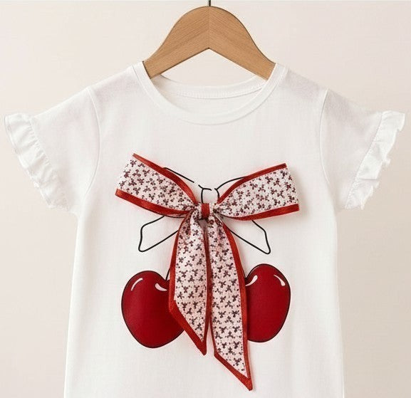 The Nile Luxuries white cotton t-shirt with cherry graphic, floral bow, and ruffled sleeves.
