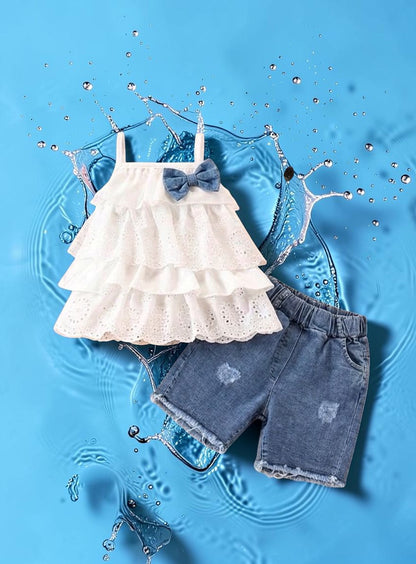 The Nile Luxuries white tiered eyelet ruffle tank with denim shorts and a denim bow accent.